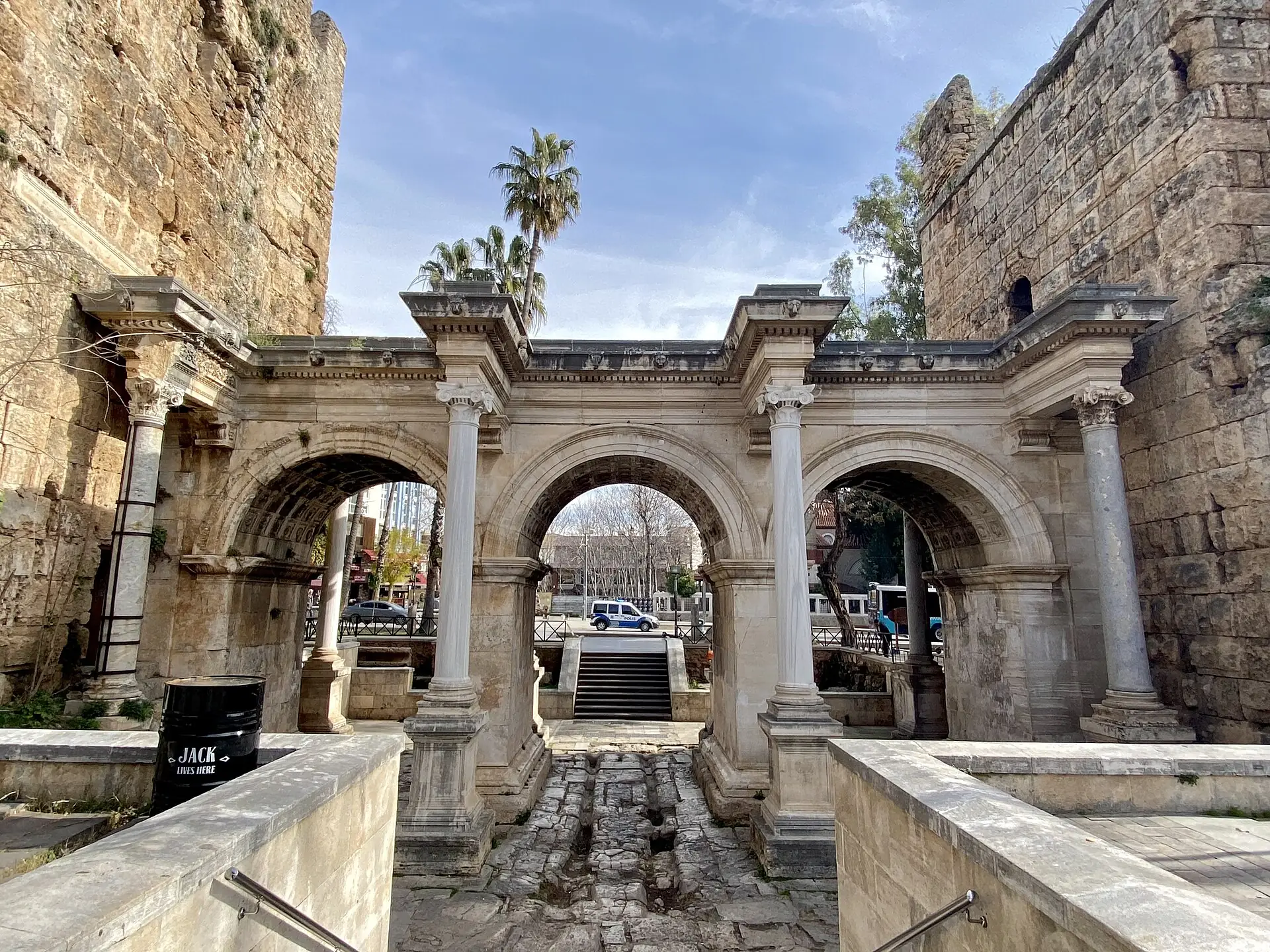 Hadrian’s Gate: three Roman stone arches between two towers, with palm trees behind