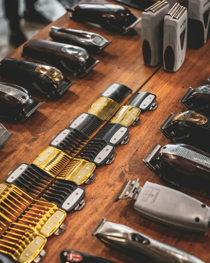 Rows of clippers and brass guards laid out on the wooden bench