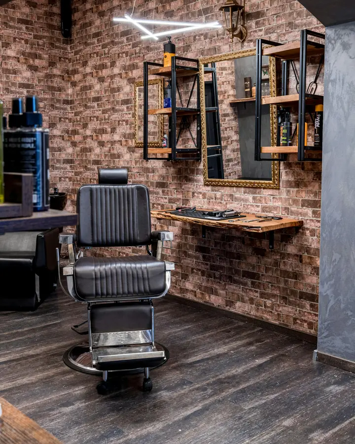 A leather barber chair by the mirror shelves and brick wall at the back of the shop